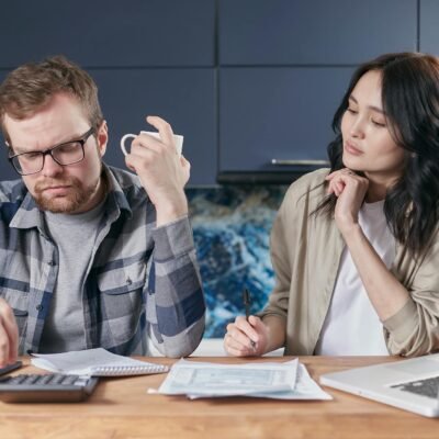 A focused young couple reviewing documents and managing their budget at home, showcasing modern financial challenges.