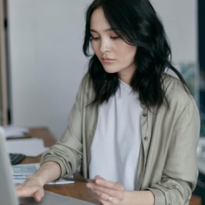 Focused young woman working on a laptop at her desk, managing finances.